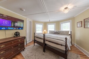A bedroom with a large TV, wooden dresser, and a bed with a wooden frame.