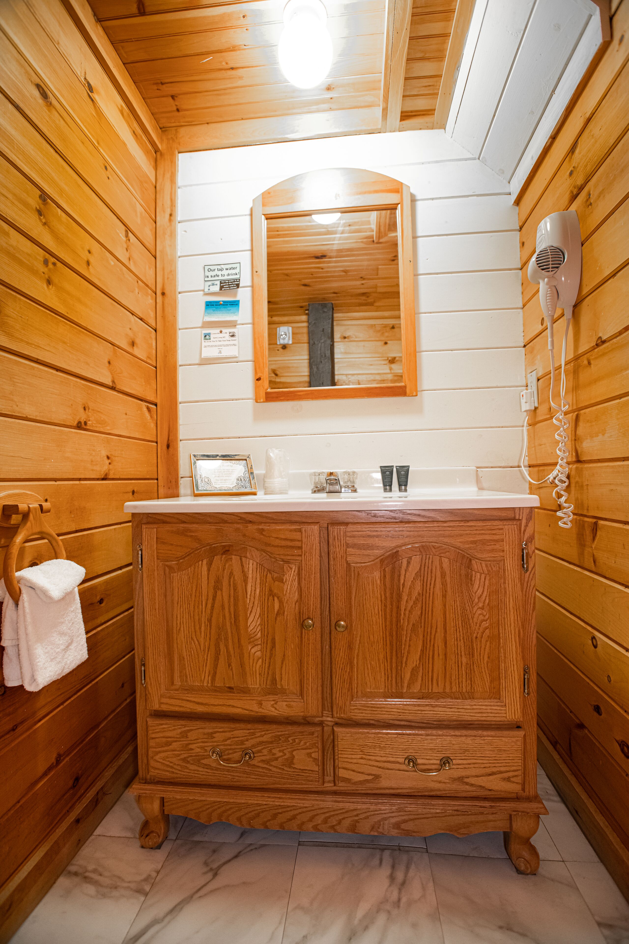 Casa de banho de cabana de madeira com toucador de madeira, espelho e secador de cabelo.