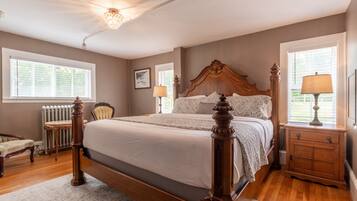 A spacious bedroom with a large bed, wooden headboard, and a nightstand with a lamp.