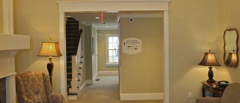 A spacious living room with a chandelier, a sofa, a patterned rug, and a staircase leading to an upper level.