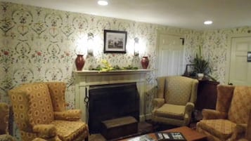 A living room with patterned wallpaper, a fireplace, and two armchairs.