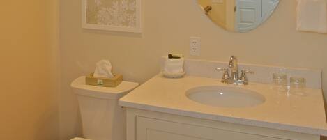 A bathroom with a toilet, sink, mirror, and towel rack.