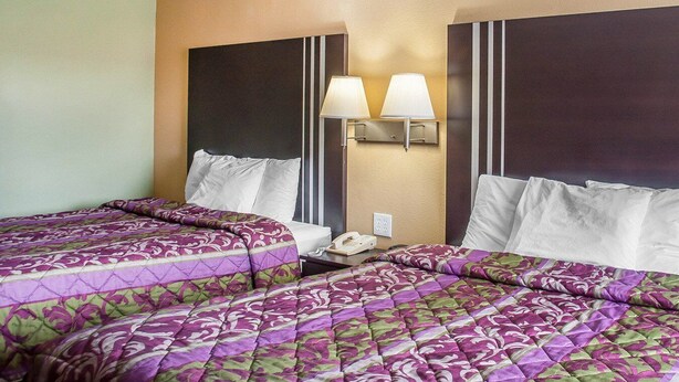A hotel room with two beds, each with a headboard, a bedside table with a lamp, and a phone. - Amherst Inn & Suites (Buffalo)