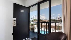 Una stanza con una porta nera, una grande finestra e vista su una piscina e degli edifici.