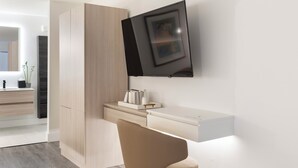 Un bagno moderno e minimalista con mobile lavabo integrato, uno specchio e un televisore a parete.