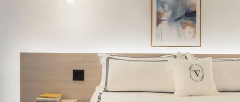 A neatly arranged hotel room with a bed, bedside table, and a wall-mounted abstract painting.