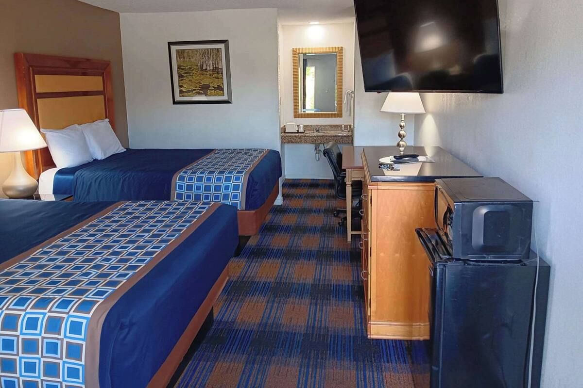 Une chambre d’hôtel avec deux lits, un bureau, une télévision et un réfrigérateur.