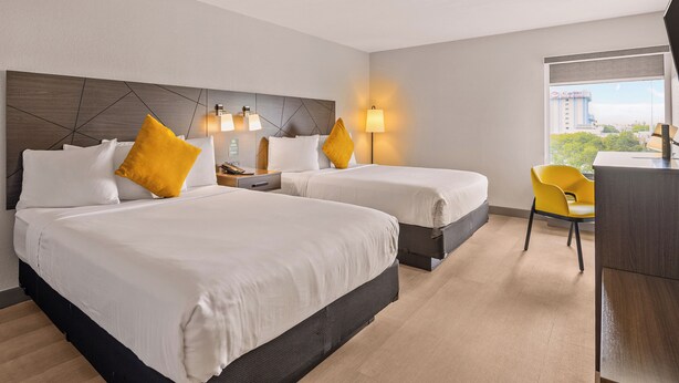 Habitación de hotel con dos camas, un escritorio y una silla.