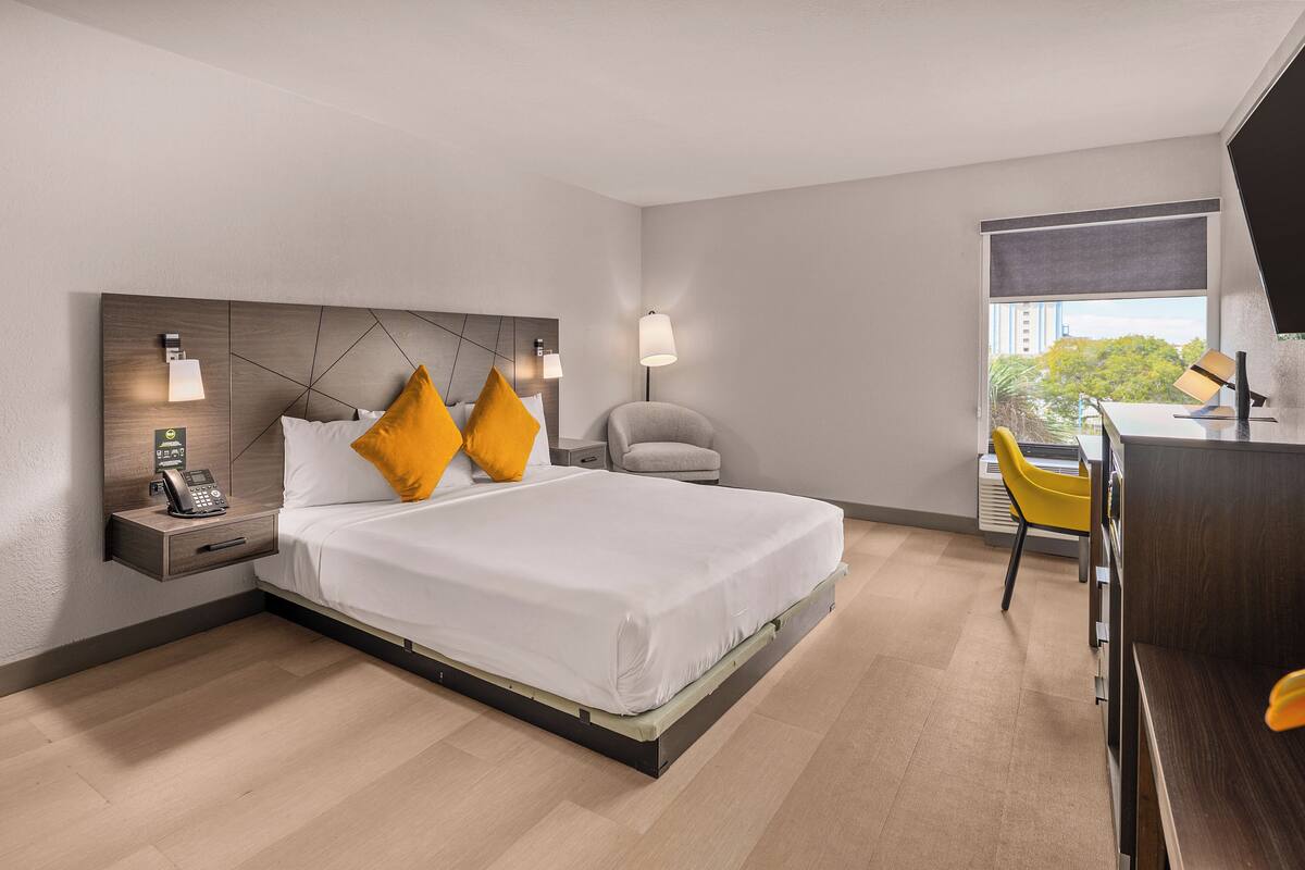 A modern hotel room with a large bed, a desk, and a chair.