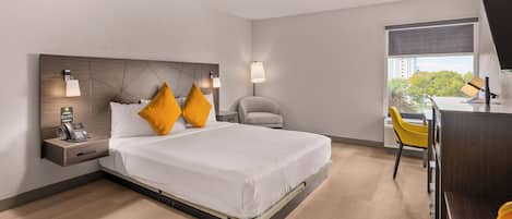 A modern hotel room with a large bed, a desk, and a chair.