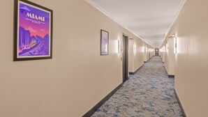Un pasillo de hotel con un cartel de Miami, suelo alfombrado y puertas a la derecha.