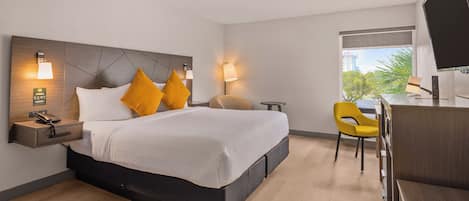 A modern hotel room with a large bed, bedside tables, a desk, and a TV.