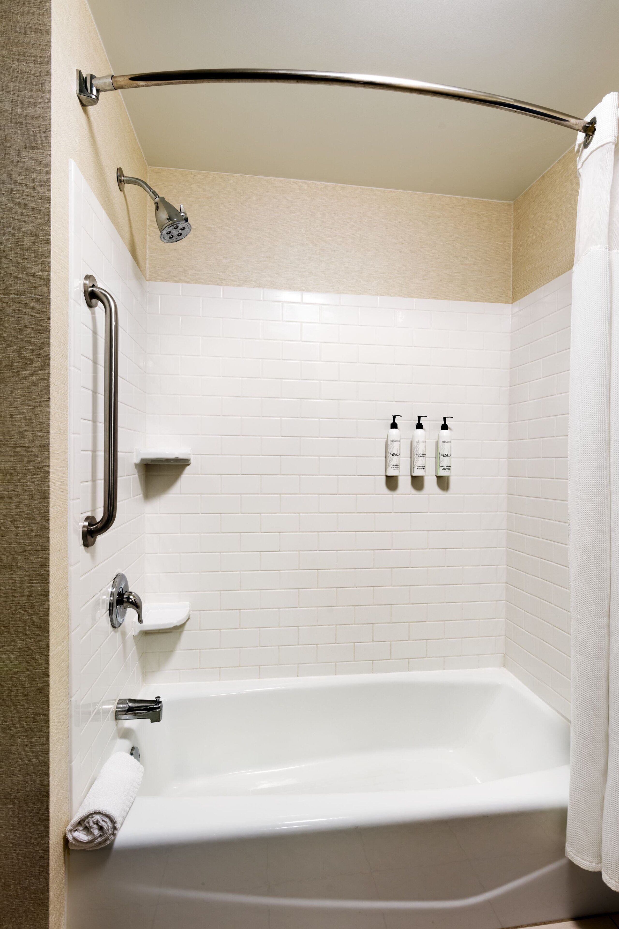 A modern bathroom with a bathtub, a shower, and a handrail.