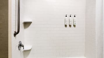 A modern bathroom with a bathtub, a shower, and a handrail.