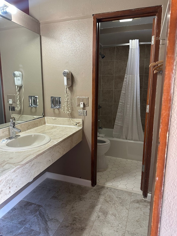 A bathroom with two sinks, a mirror, a shower with a curtain, and a toilet.