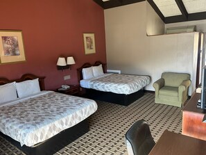 A hotel room with two beds, a desk, a chair, and a television.