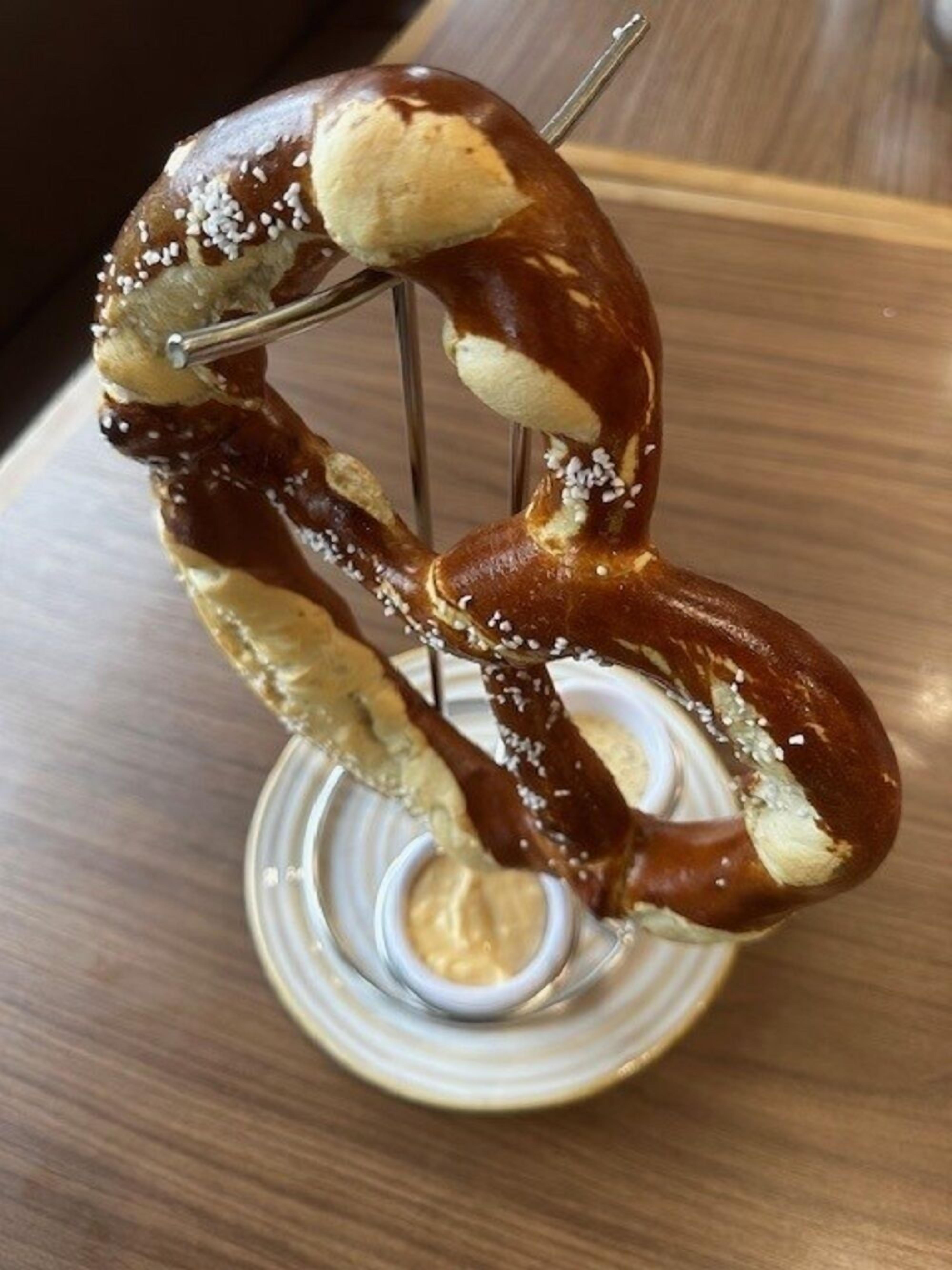 A pretzel on a stand with a dipping sauce.