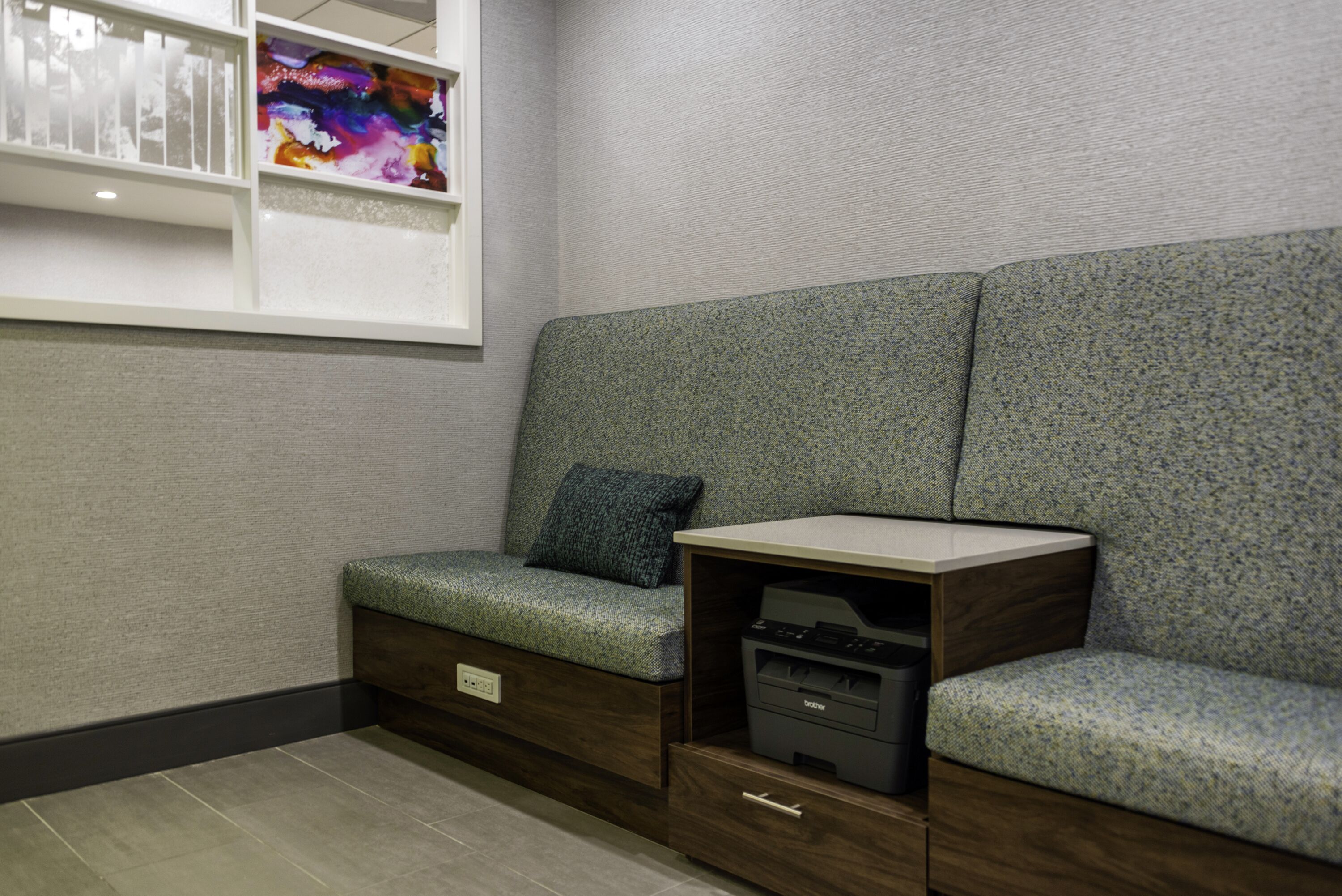 A seating area with a sofa, a small table, and a printer drawer.