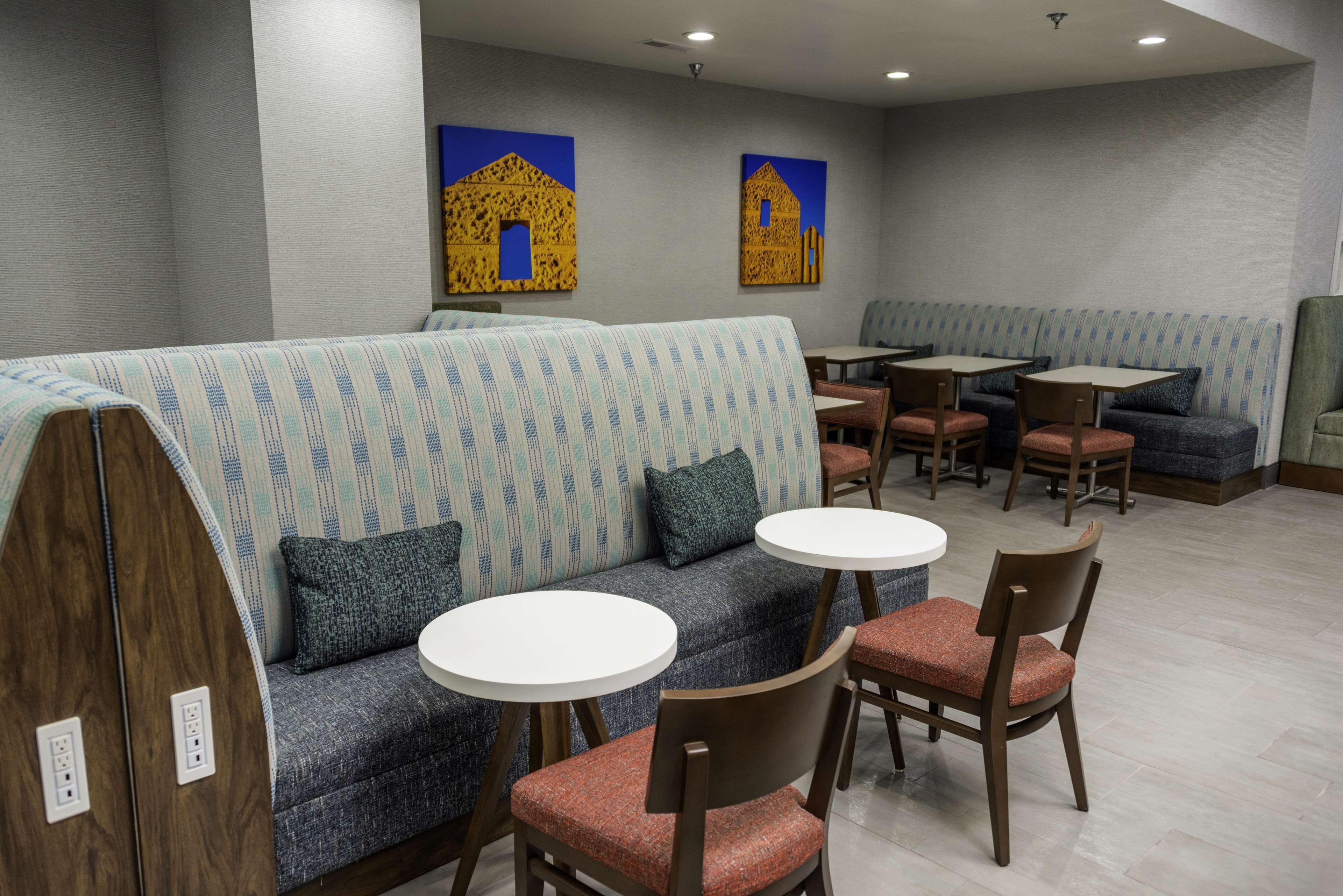 A restaurant with a long counter, multiple tables, and a seating area with sofas and chairs.