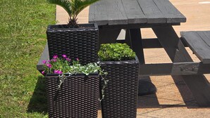 Outdoor seating with black woven planters containing plants and flowers.