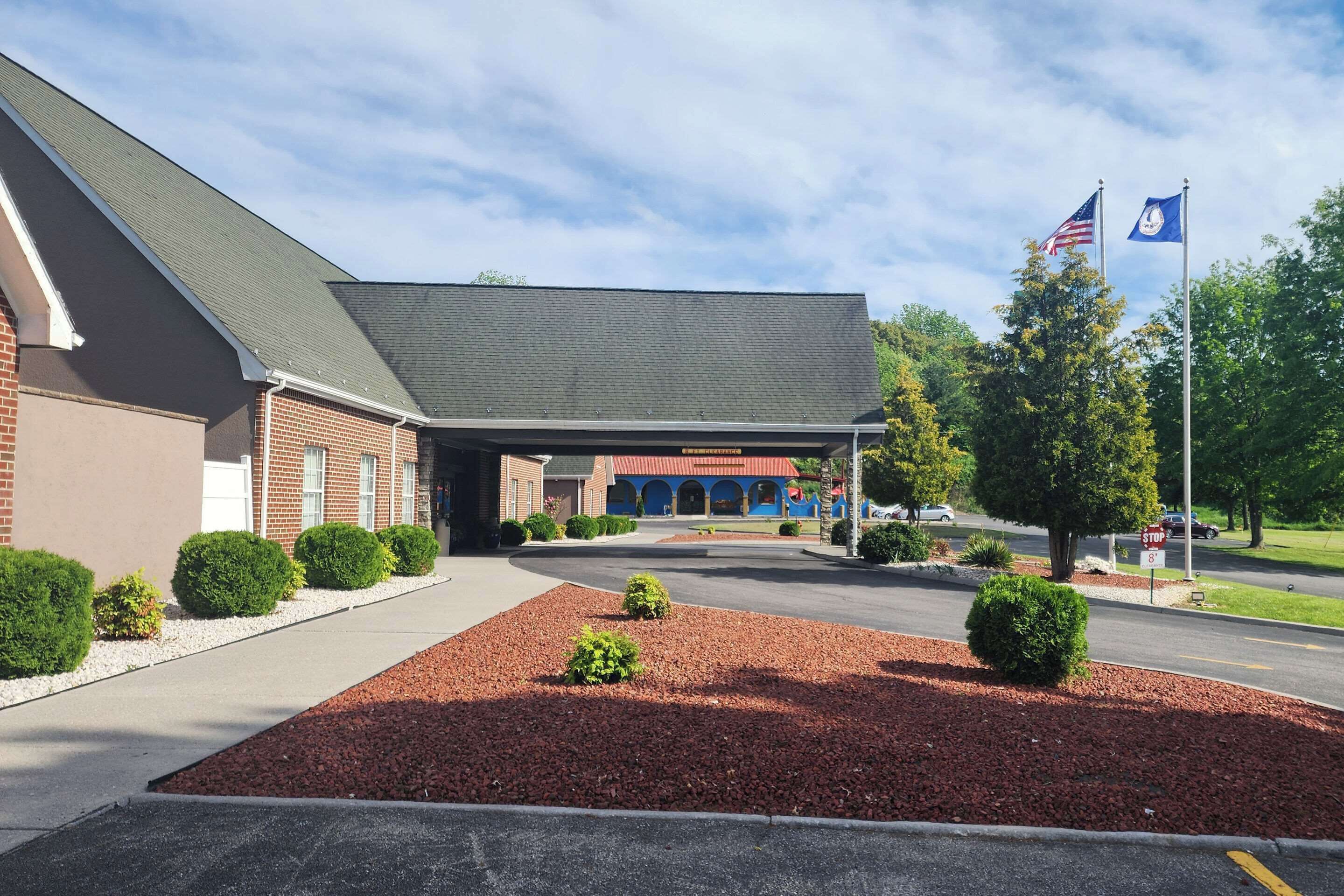 A building with a brick facade, a covered entrance, and a parking lot with red mulch landscaping.
