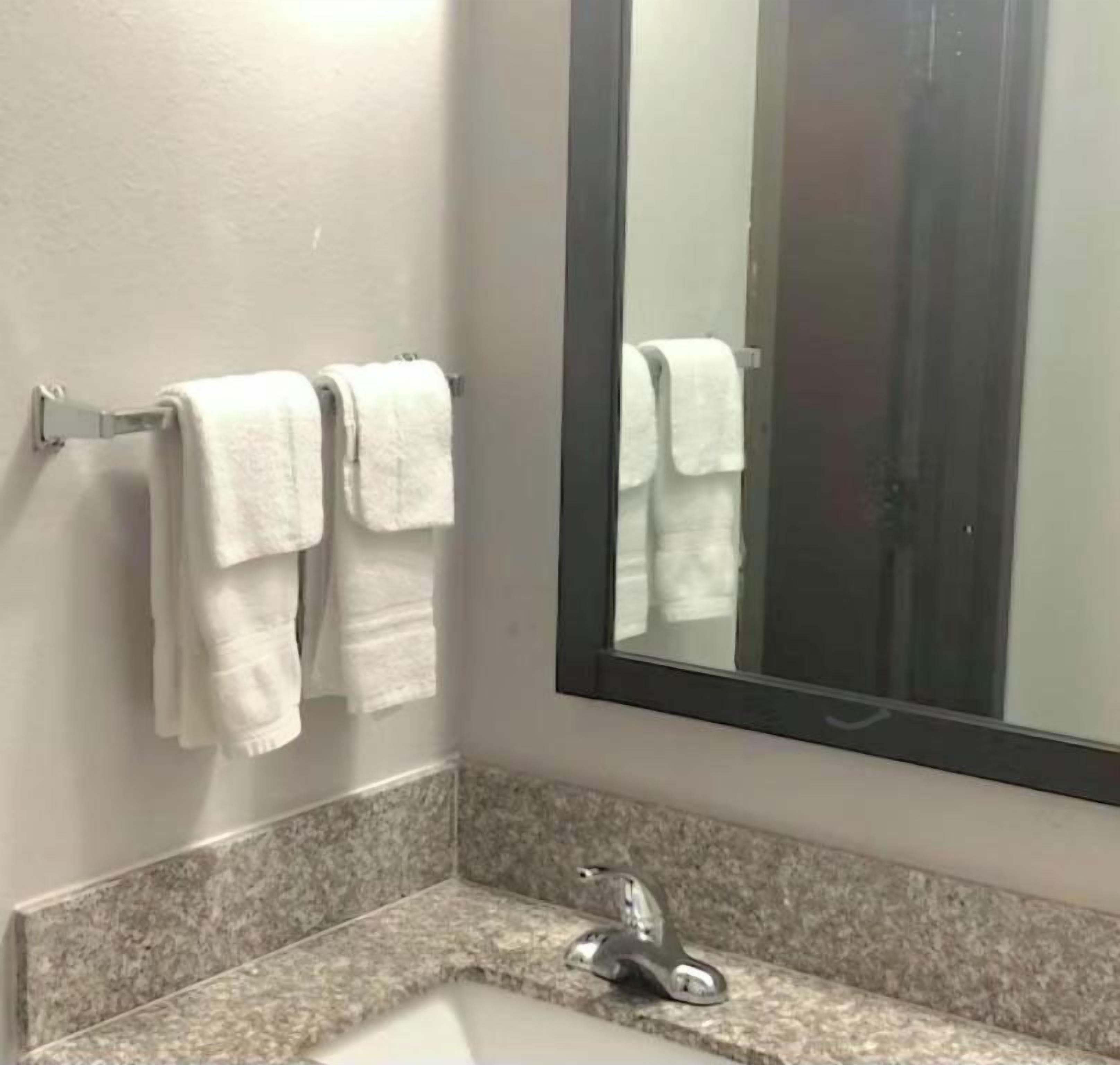 A bathroom with a sink, mirror, and two towels on a rack.