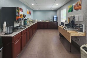 A kitchen area with a coffee station, a microwave, and a refrigerator.