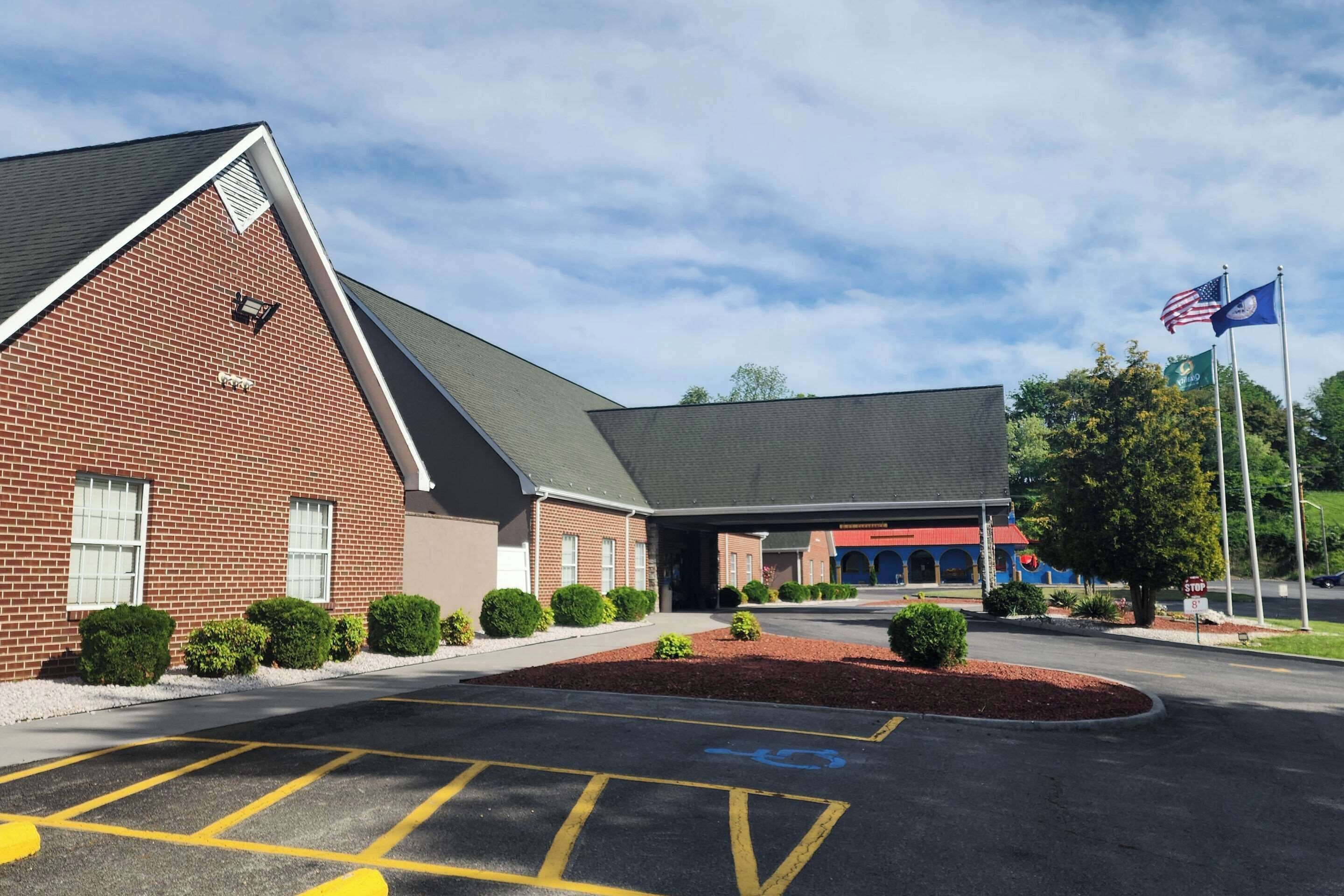 A brick building with a covered entrance, a parking lot with handicapped accessible spaces, and American flags.
