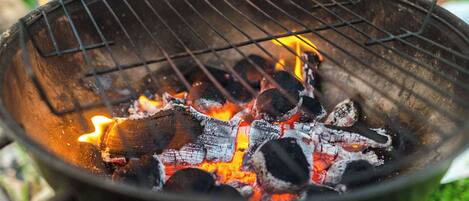 A close-up of a grill with burning charcoal and flames.