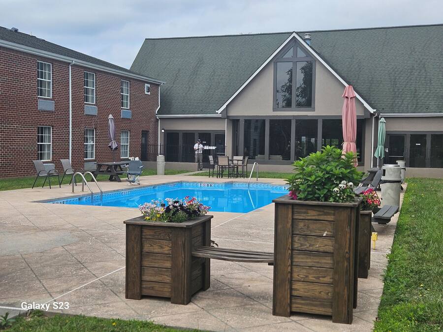 A backyard with a swimming pool, outdoor seating, and a brick building.