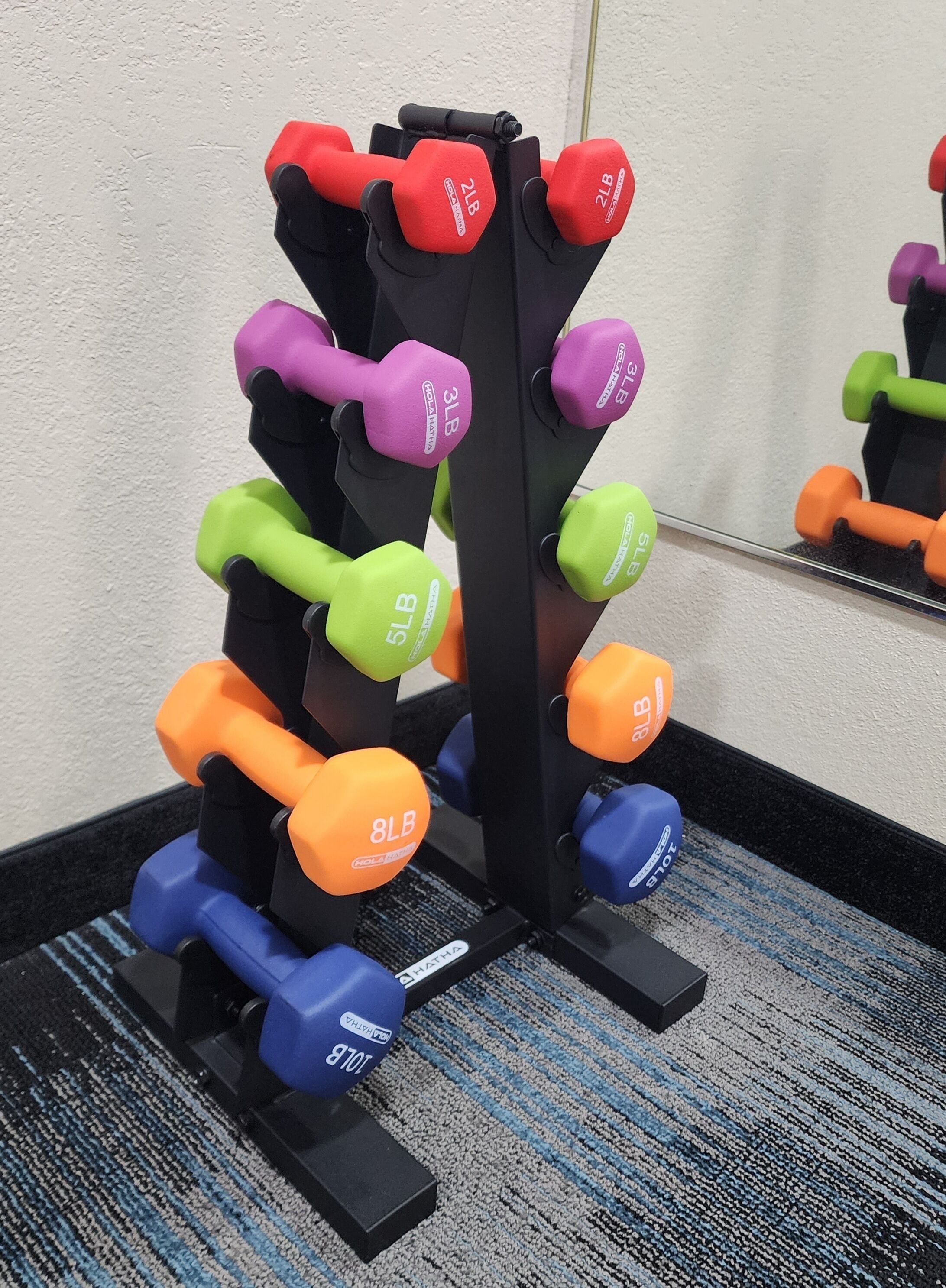A set of adjustable dumbbells in various weights and colors, mounted on a black stand.