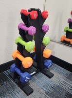 A set of adjustable dumbbells in various weights and colors, mounted on a black stand.