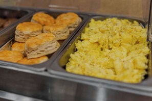 Buffet com pães, biscoitos e ovos mexidos.