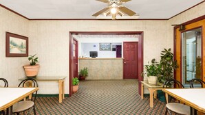 A hotel lobby with a reception desk, a ceiling fan, and potted plants. - Knights Inn Galax (Galax)