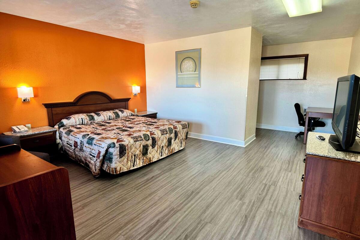 Ein Hotelzimmer mit Bett, Schreibtisch, Computer und Fernseher.