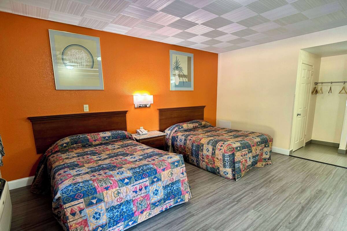 Ein Hotelzimmer mit zwei Betten, einem Nachttisch, einer Lampe und einer Tür.