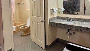 A bathroom with a toilet, sink, and shower area. - Knights Inn Galax (Galax)
