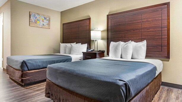 Une chambre d’hôtel avec deux lits, des têtes de lit en bois, une table de chevet avec une lampe et une carte murale.