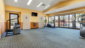 Un centre de remise en forme équipé de matériel d’exercice, doté de grandes fenêtres et d’un tapis à motifs.