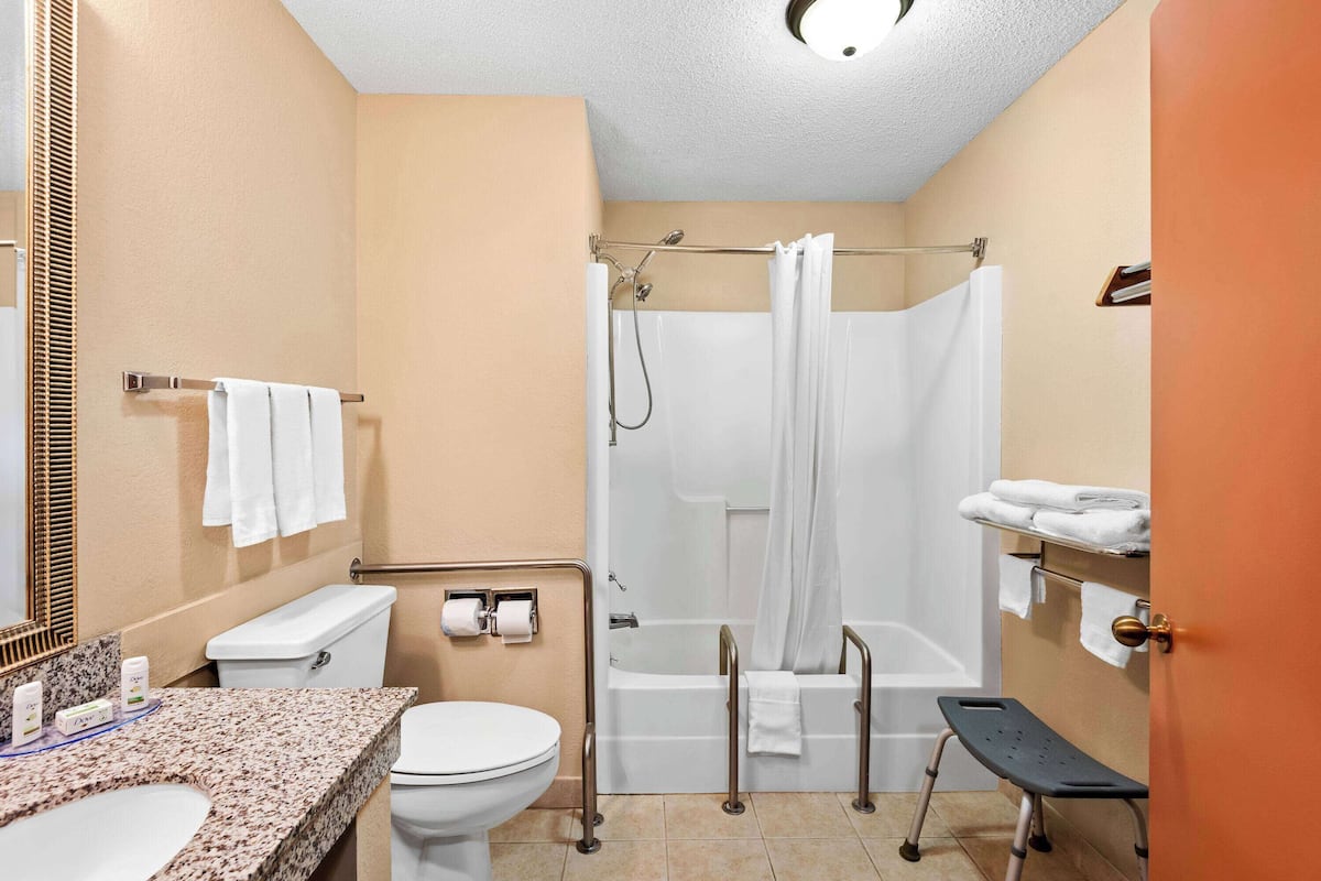 Ein Badezimmer mit Toilette, Waschbecken, Dusche und einer kleinen Stufe.