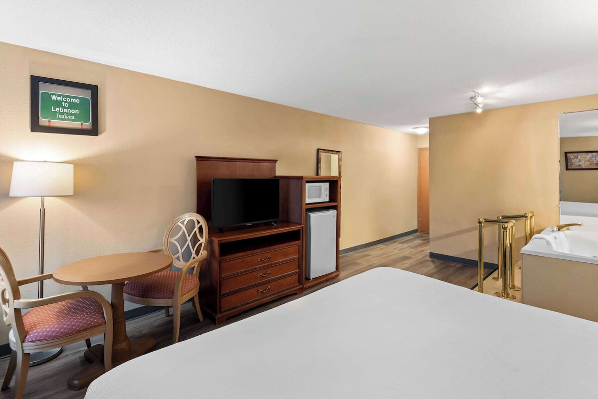 Ein Hotelzimmer mit Bett, Schreibtisch mit Stuhl, Fernseher, Minikühlschrank und Mikrowelle.