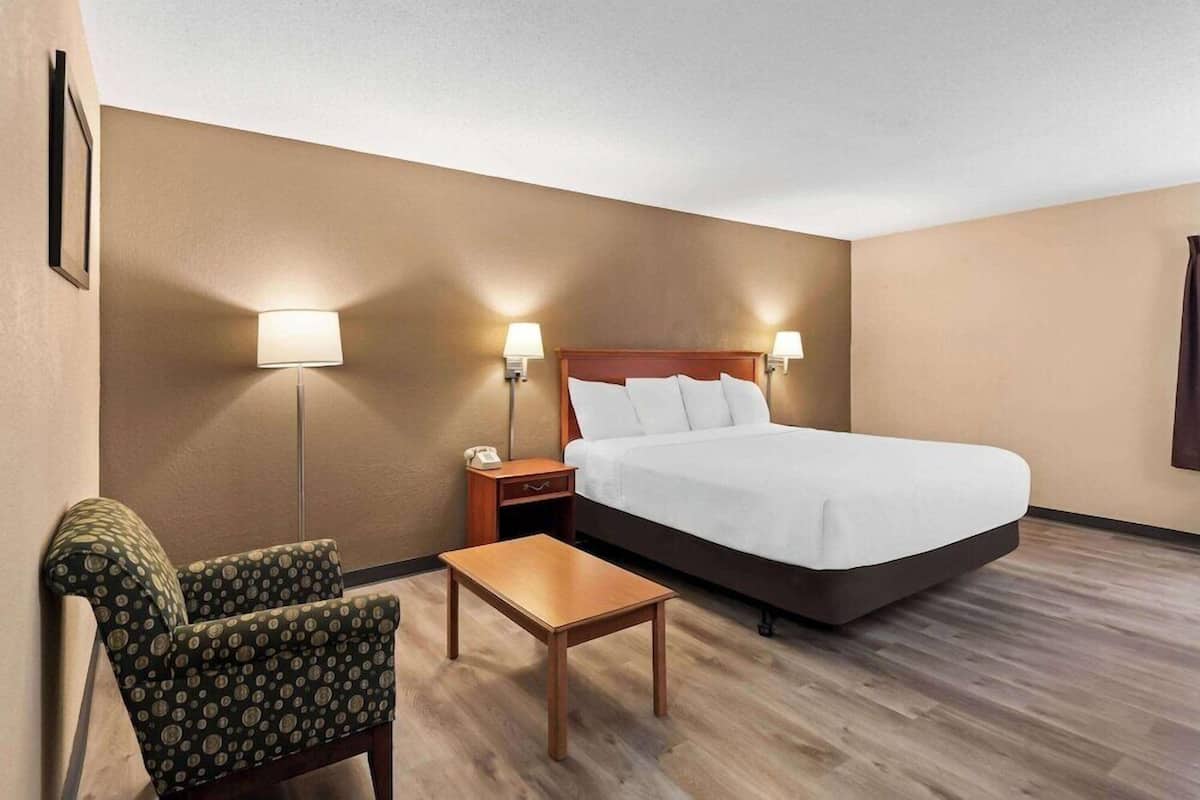 Ein Hotelzimmer mit Bett, Stuhl, Nachttisch und Tisch.