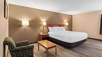 A hotel room with a bed, a nightstand, a chair, and a small table.