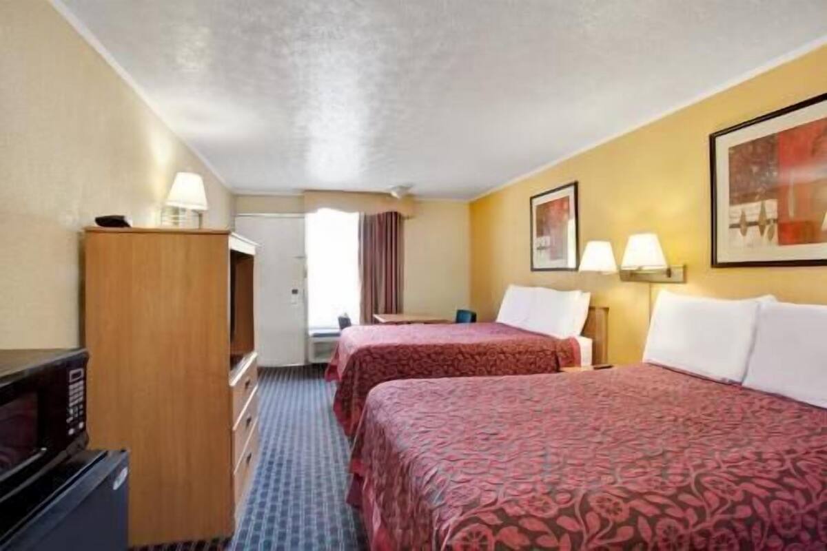 Habitación de hotel con dos camas, un escritorio, un microondas y un armario.