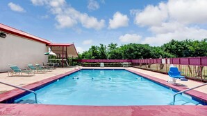 Una piscina con sillas de descanso y un área de estar techada.