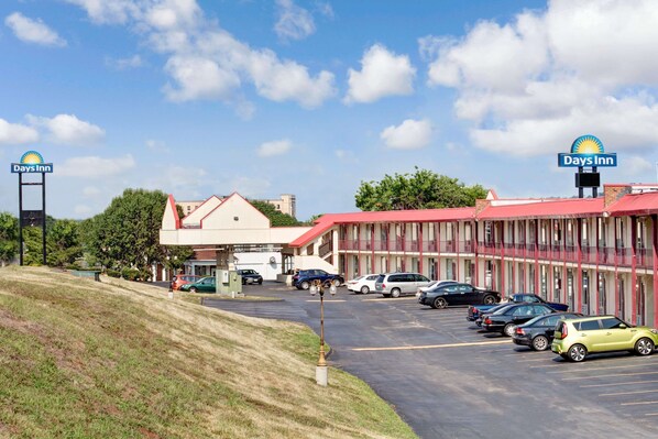 Un hôtel Days Inn doté d’un parking, d’une colline verdoyante et d’un bâtiment avec un toit rouge.