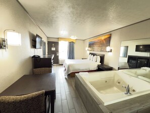 Une chambre d’hôtel équipée d’un lit, d’un bureau, d’une chaise, d’une grande baignoire et d’un téléviseur.
