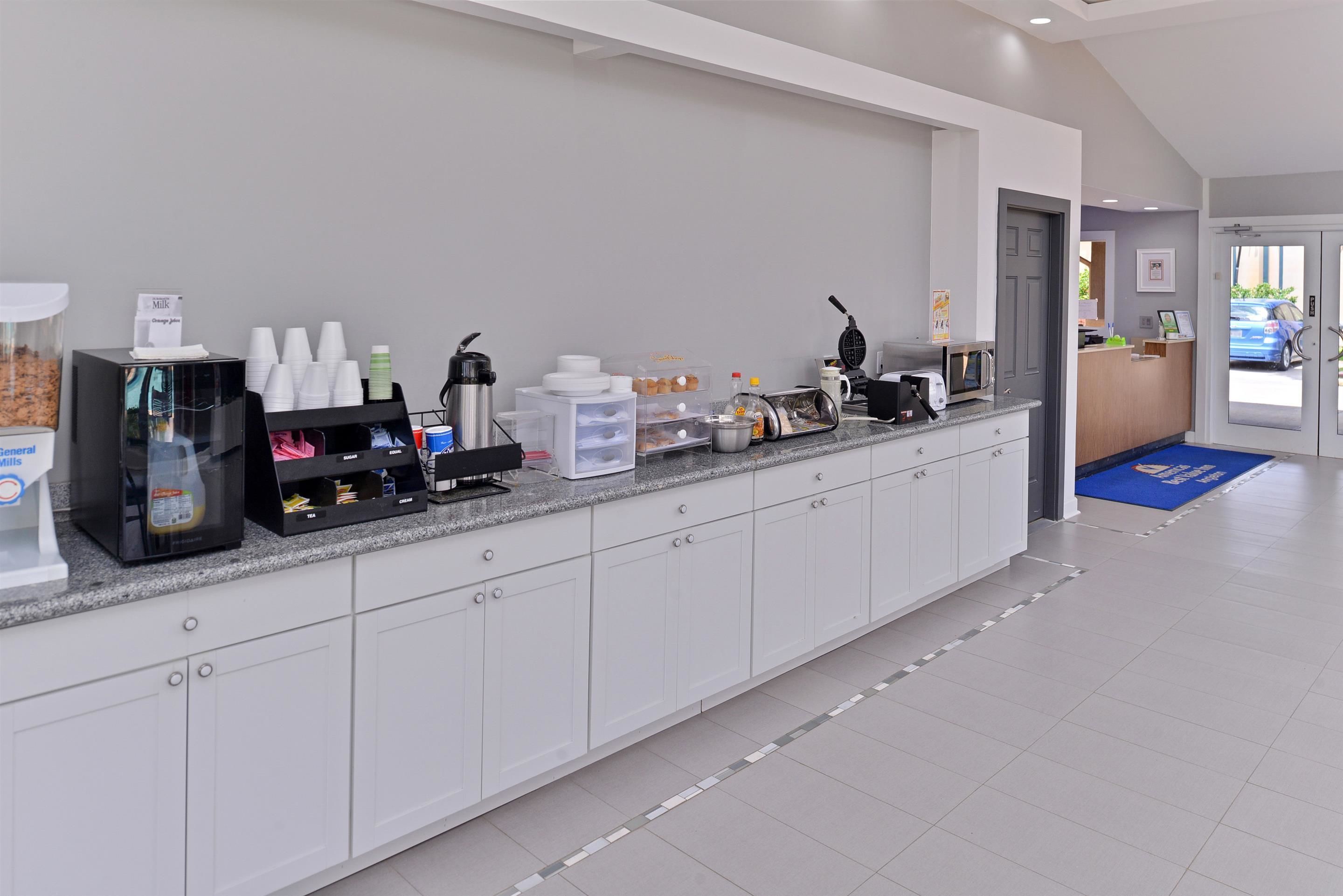 A clean, modern reception area with a coffee station, a microwave, and a counter with various items.