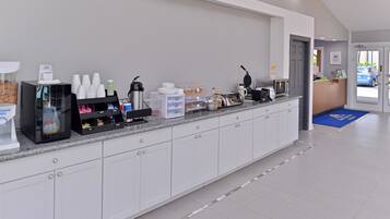 A clean, modern reception area with a coffee station, a microwave, and a counter with various items.