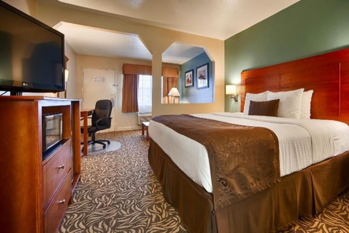 A hotel room with a bed, a television, a desk, and a chair.